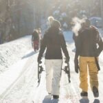 person holding snow ski blades while walking on snowy mountain during daytime