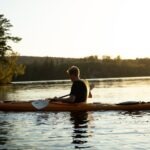 woman in yellow shirt riding on brown kayak on lake during daytime