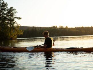 woman in yellow shirt riding on brown kayak on lake during daytime